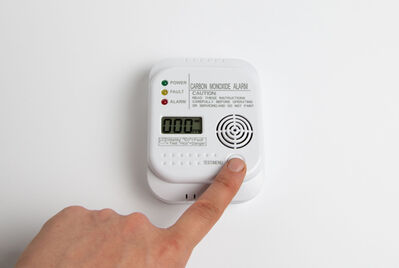 Someone pushing a button on a carbon monoxide detector