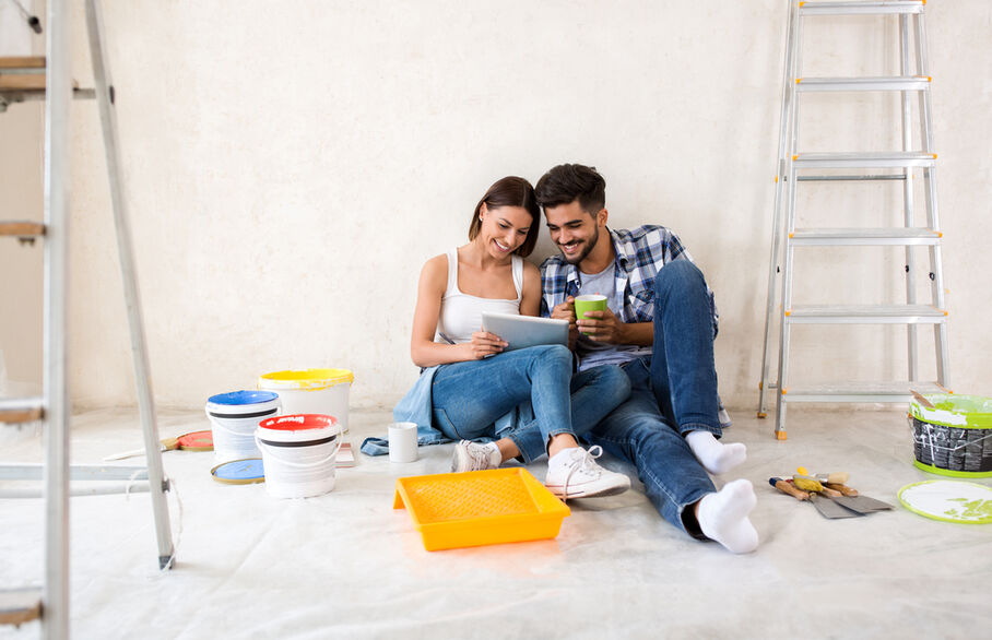 Two people sitting on the floor surrounded by paint cans