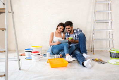 Two people sitting on the floor surrounded by paint cans