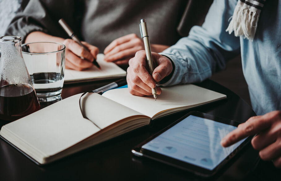 Two people writing in notebooks