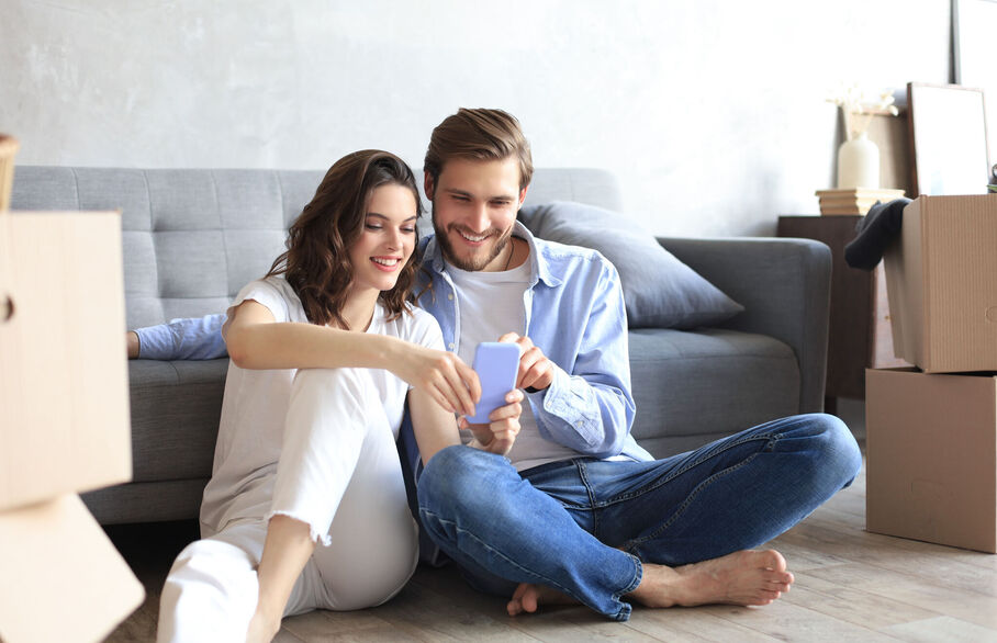 Two people sitting on the floor looking at a phone screen