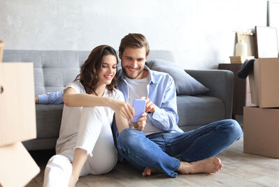 Two people sitting on the floor looking at a phone screen