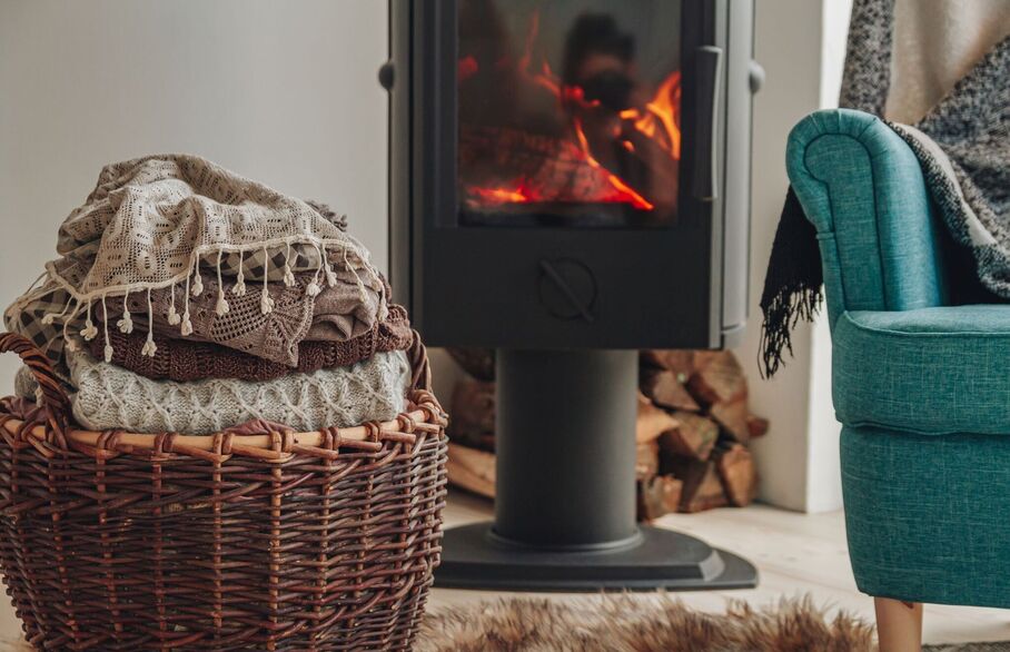 A basket of blankets and an armchair sat in front of a log fire