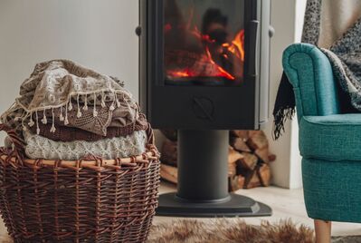 A basket of blankets and an armchair sat in front of a log fire