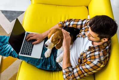 Man with a laptop and dog in his lap