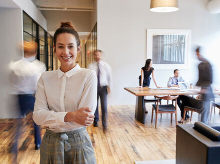 Portrait of young white woman in a busy modern workplace