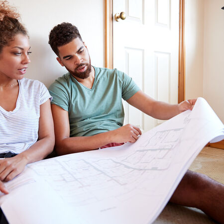 Couple sitting on floor looking at floorplans